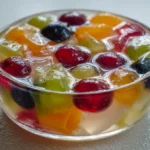 Gelatin dessert with fruit pieces in glass ramekin with soft indoor lighting