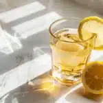clear glass of gelatin weight loss drink with lemon slice on white marble counter showing the 3 ingredient recipe for appetite suppression
