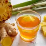 Costa Rican tea for weight loss in clear glass with fresh pineapple ginger and lemongrass on white marble