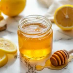 honey trick raw honey in clear glass with fresh lemon on white marble counter
