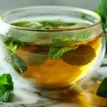 Peppermint tea before bed in clear glass cup with fresh mint leaves floating