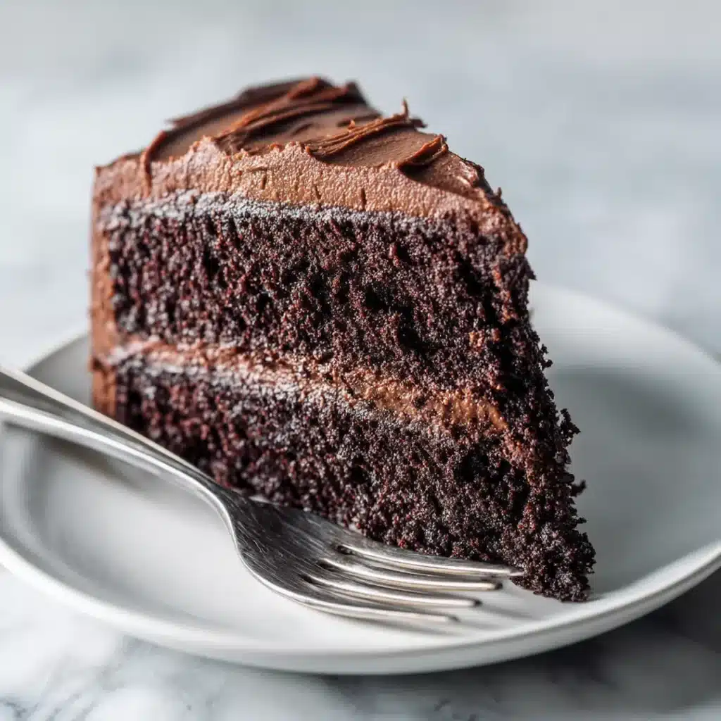 close-up cross section of moist vegan chocolate cake slice showing dark tender crumb and frosting layers