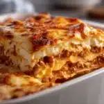 Best lasagna recipe with ricotta meat sauce and three cheese layers in white baking dish