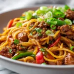 Dirty spaghetti recipe in a white bowl with brown meat sauce and green onions