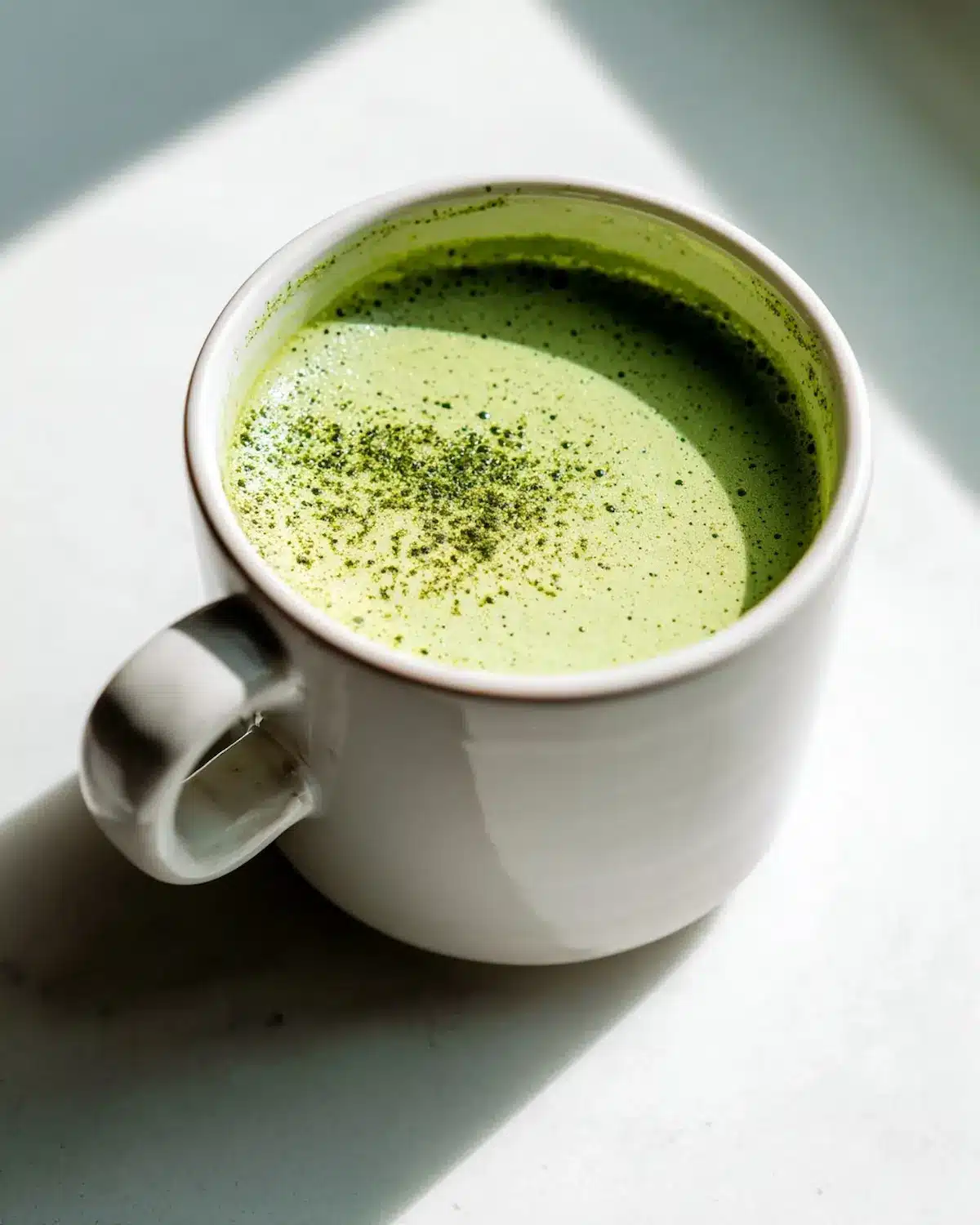 creamy Japanese green tea EGCG matcha latte in a white mug on a light counter