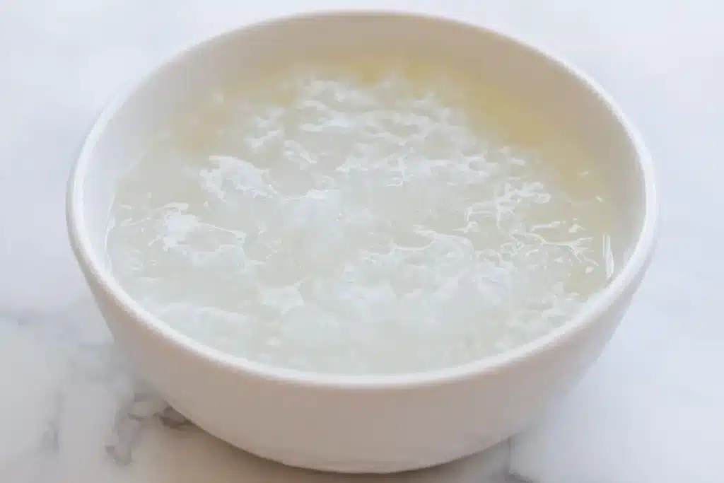 Unflavored gelatin powder blooming in cold water in a white bowl for lipojaro jello recipe