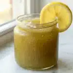 Sea moss trick recipe golden gel tonic in clear glass with lemon slice on white marble surface