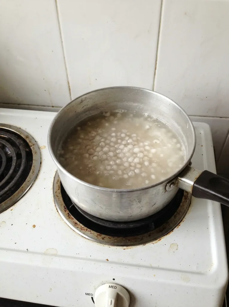 Sago pearls simmering in a pot for Mango Sago Pudding