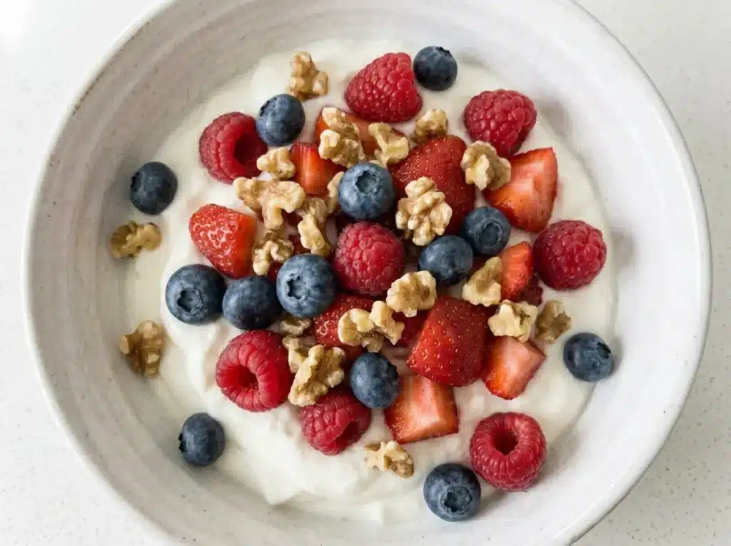 dr phil low sugar recipe greek yogurt bowl with fresh blueberries raspberries and chopped walnuts on white quartz