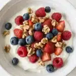 dr phil low sugar recipe greek yogurt bowl with fresh blueberries raspberries and chopped walnuts on white quartz