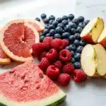 Close-up of colorful fresh fruits arranged on a white marble surface
