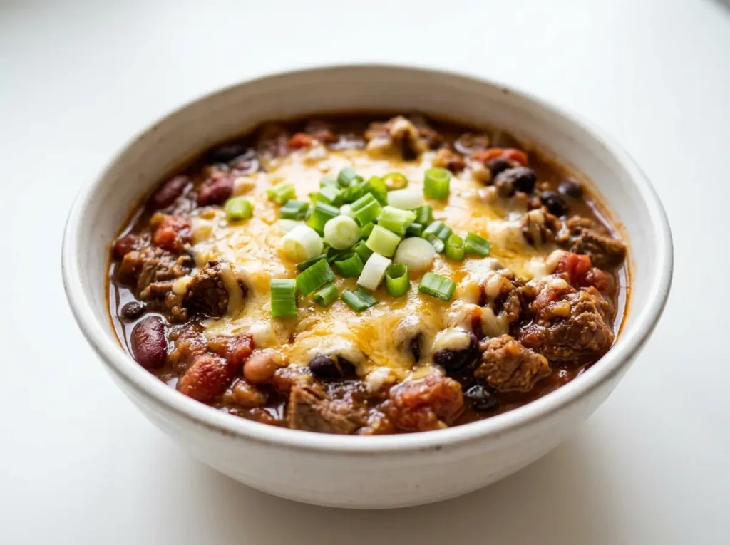 11 Easy Family Dinner Recipes That Actually Work 3 Bowl of homemade beef chili topped with cheese and green onions on a white plate.