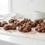 A plate of chocolate no bake cookies on white parchment with a clean bright background.